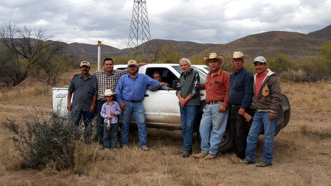 Group of people standing in a ojo laguna area with a white truck.