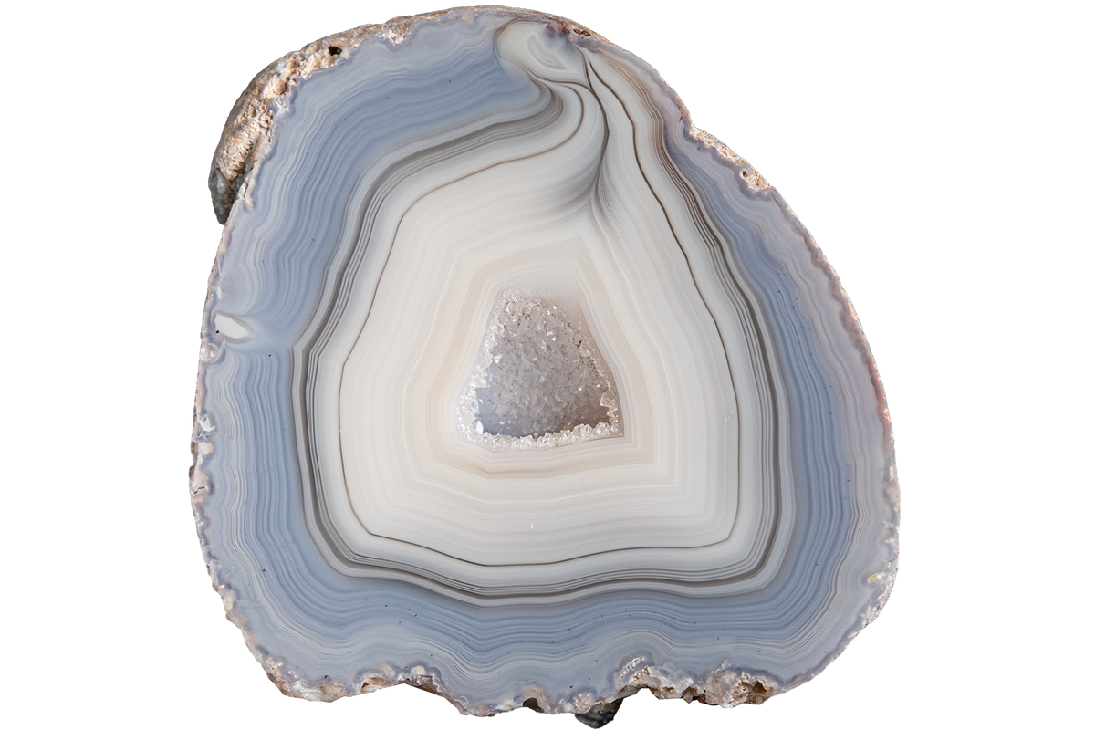 A polished cross-section of agate or jasper stone showing concentric bands of pale blue, gray, white, and black, with a small crystalline cone in the center, isolated on a white background.