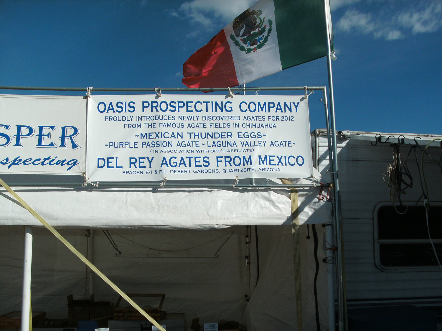 Oasis Prospecting Company sign with Mexican flag against a blue sky